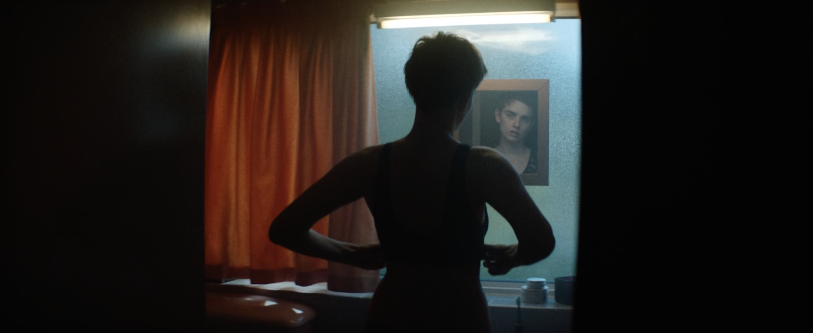 a woman standing in front of a window in a dark room