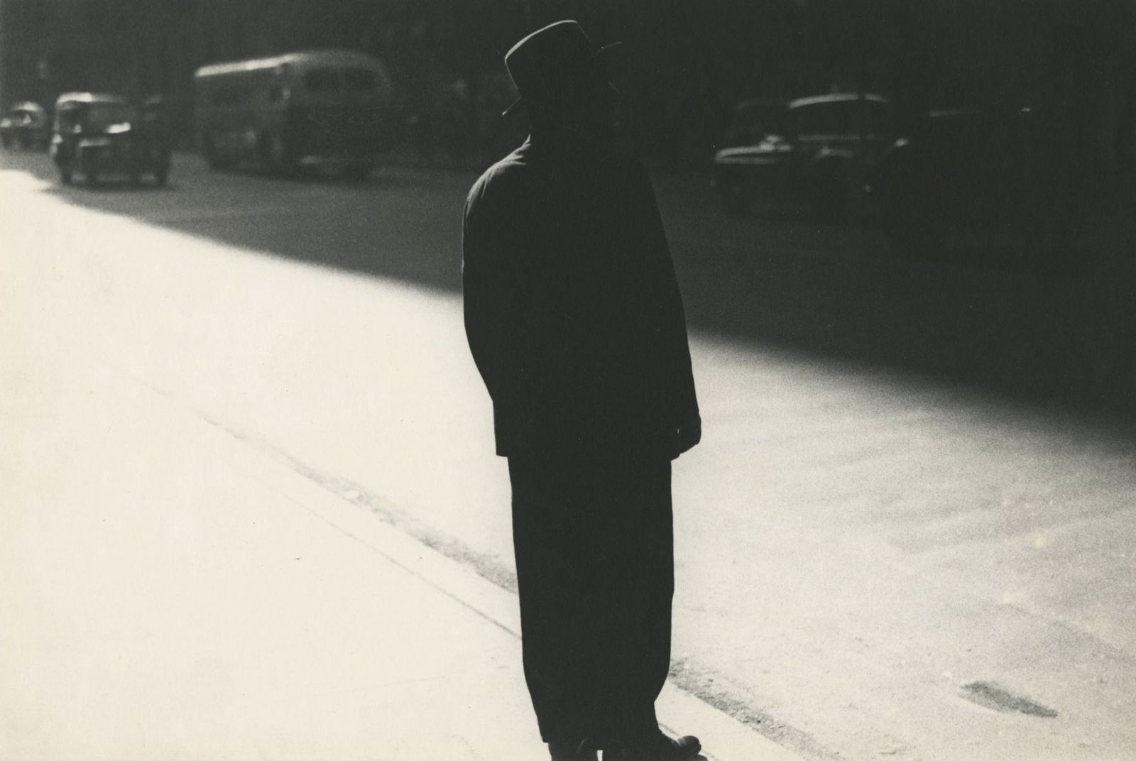 a black and white photo of a man standing on the side of a road