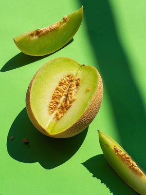 a whole and cut melon on a green surface