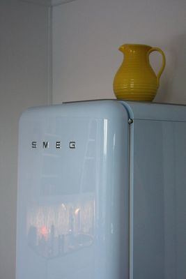 a yellow vase sitting on top of a refrigerator