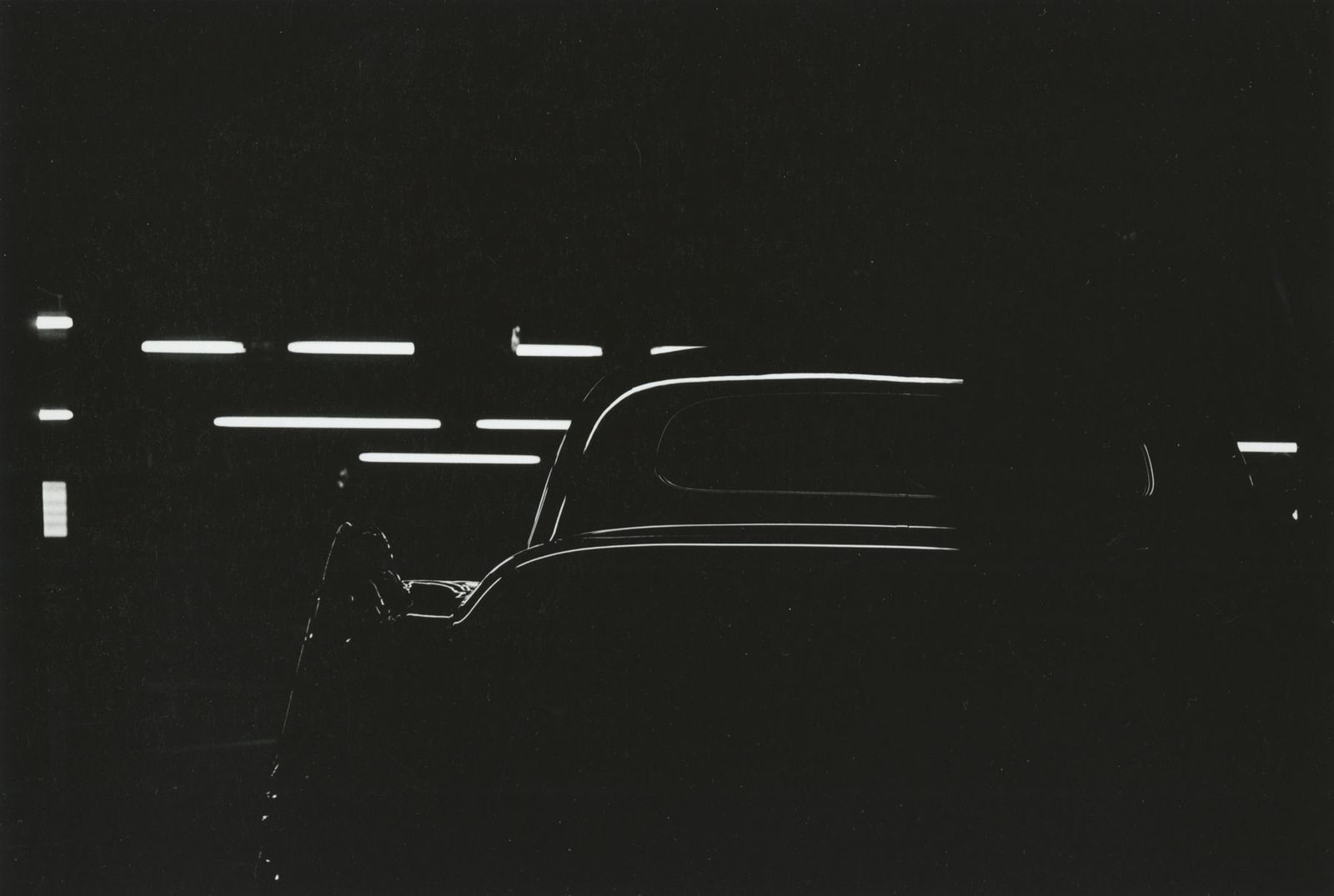 a black and white photo of a car in the dark