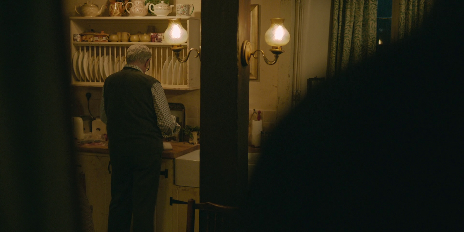 a man standing in a kitchen next to a sink