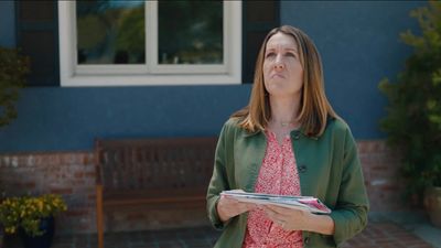 a woman holding a binder in front of a house