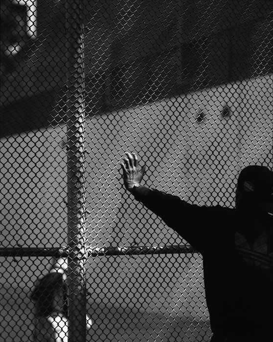 a person reaching up towards a chain link fence