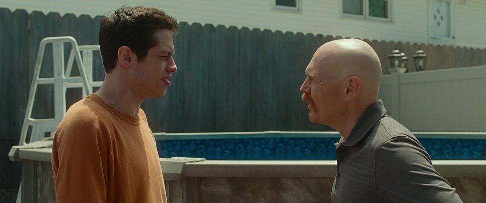 two men standing next to each other near a pool