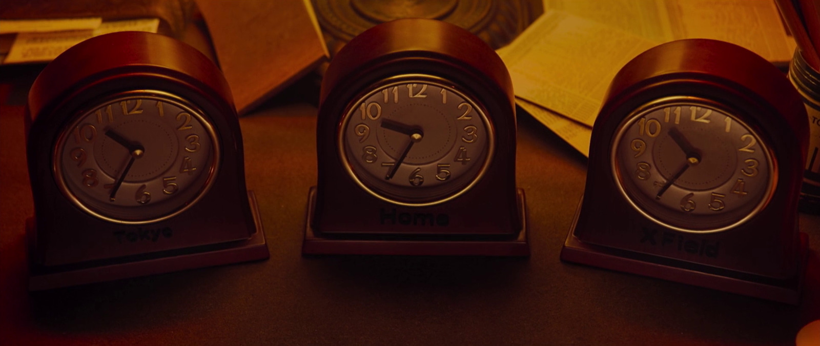 three clocks sitting on top of a table next to a book