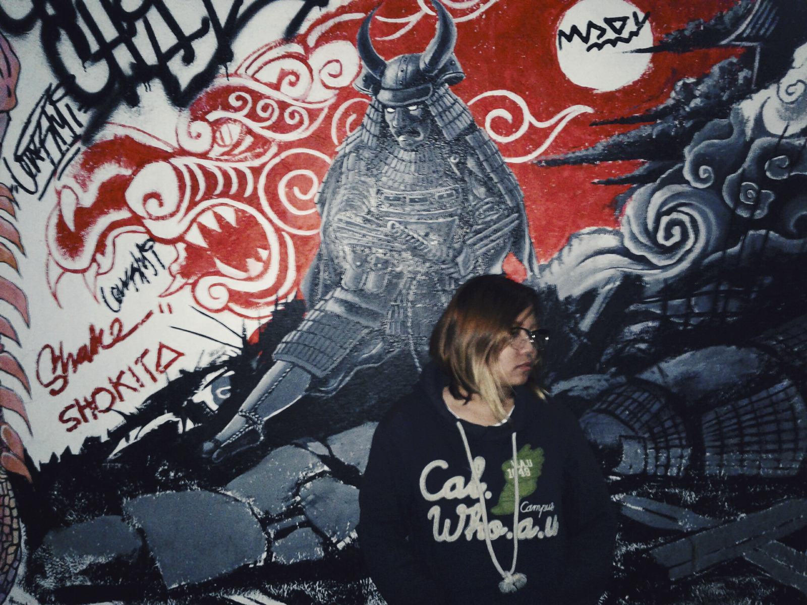 a woman standing in front of a wall covered in graffiti