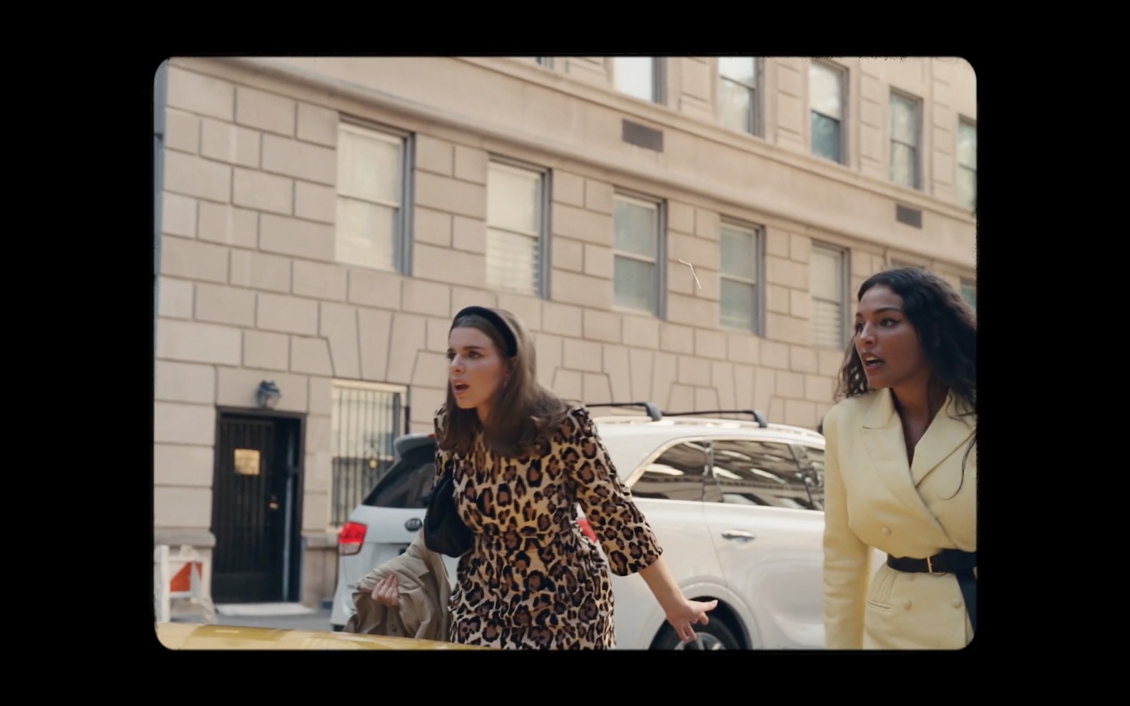 two women walking down the street in front of a building