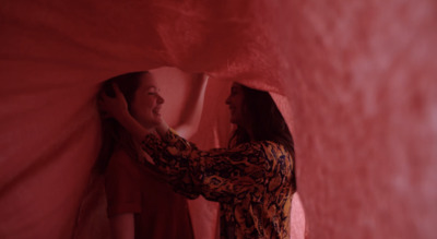 two women are standing in a red room