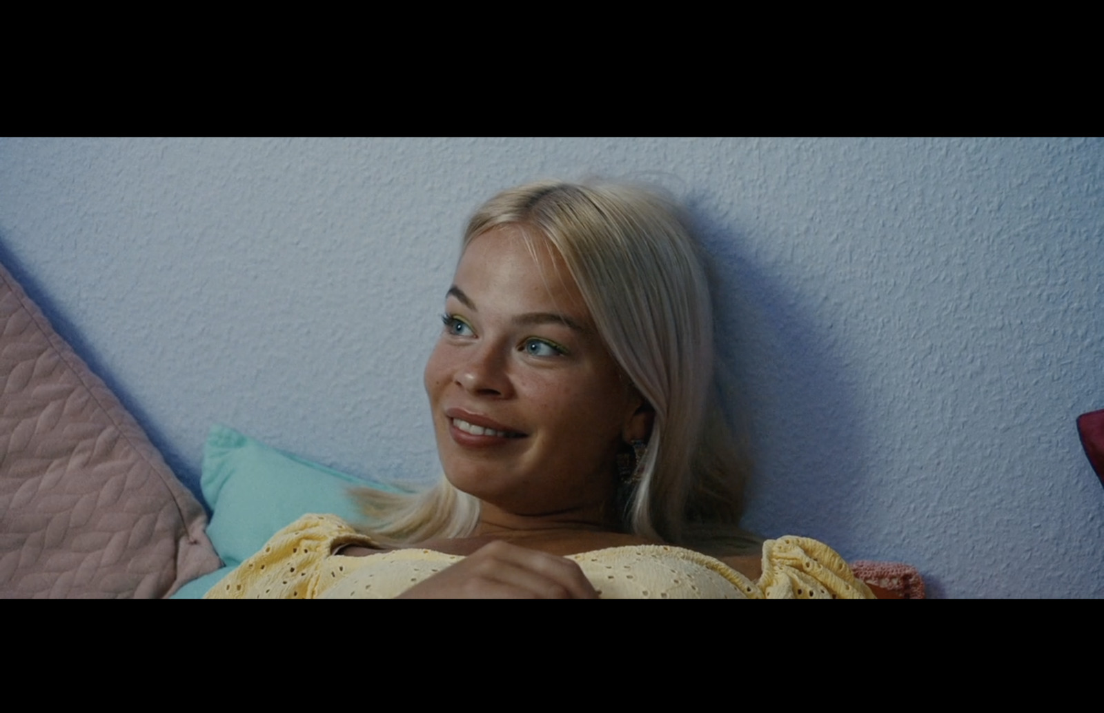 a woman laying on a bed with a blue wall behind her