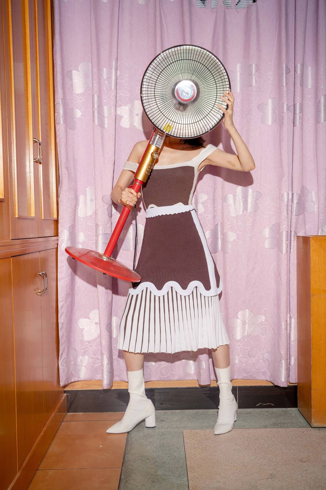 a woman in a dress holding a fan in front of her face