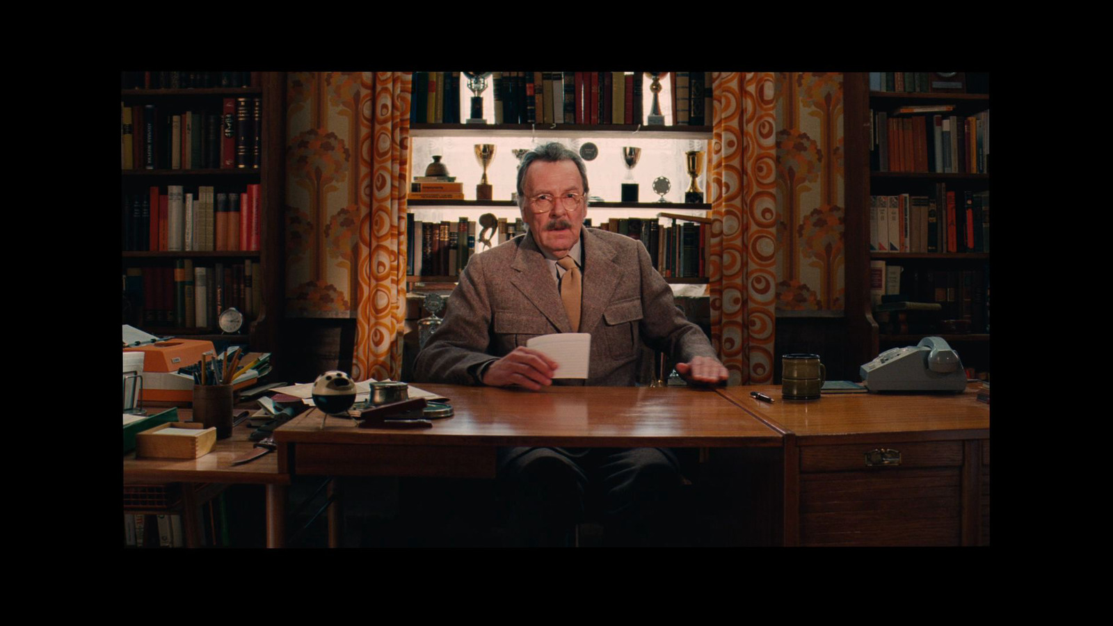 a man sitting at a desk in front of a book shelf