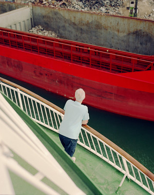 a man standing on a bridge next to a red boat