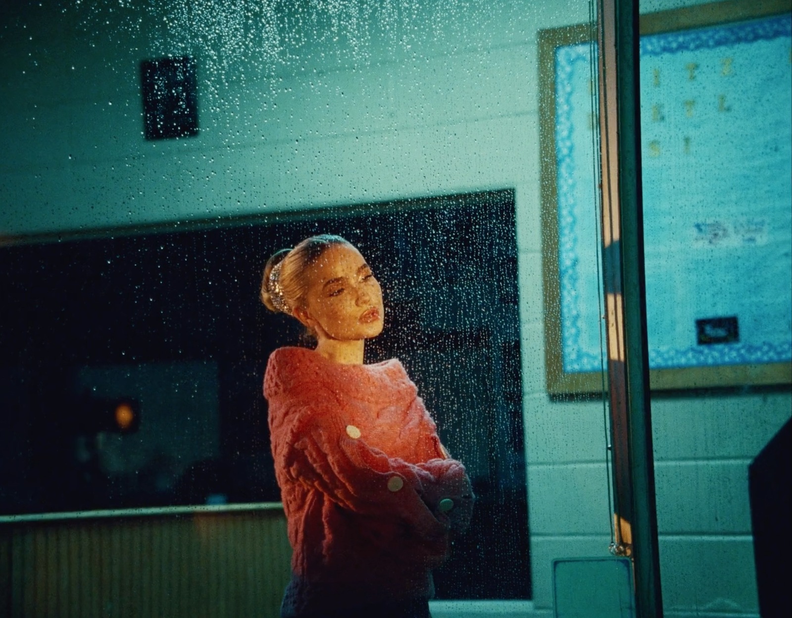 a woman standing in front of a window in the rain