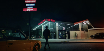 a man standing in front of a gas station at night