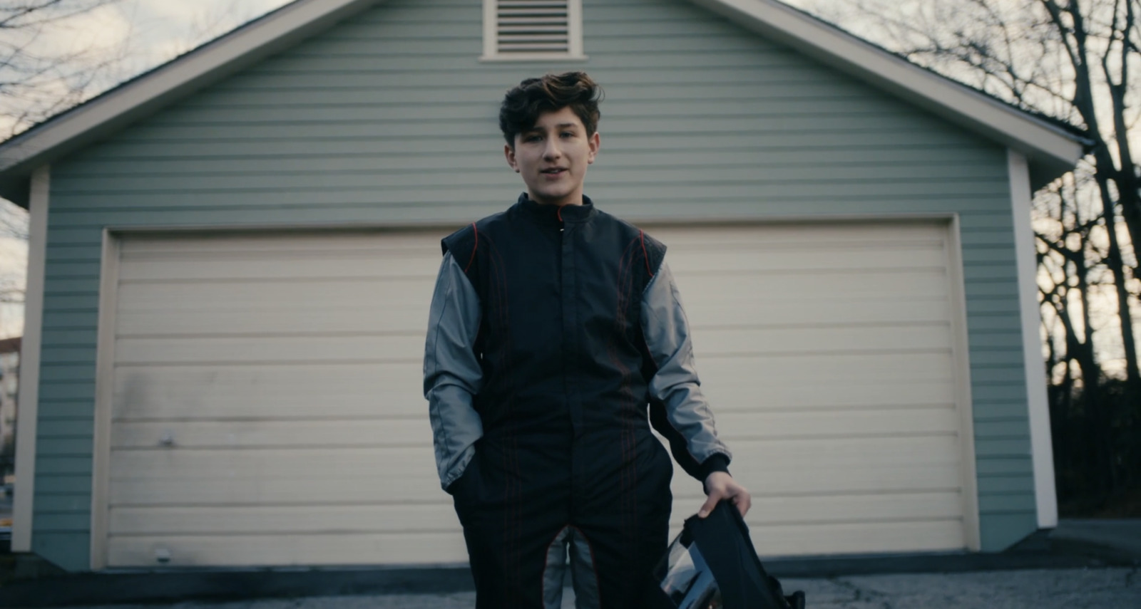 a man standing in front of a garage holding a skateboard