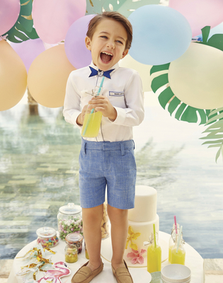 a young boy standing in front of a cake