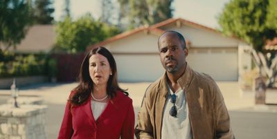 a man and a woman standing in front of a house