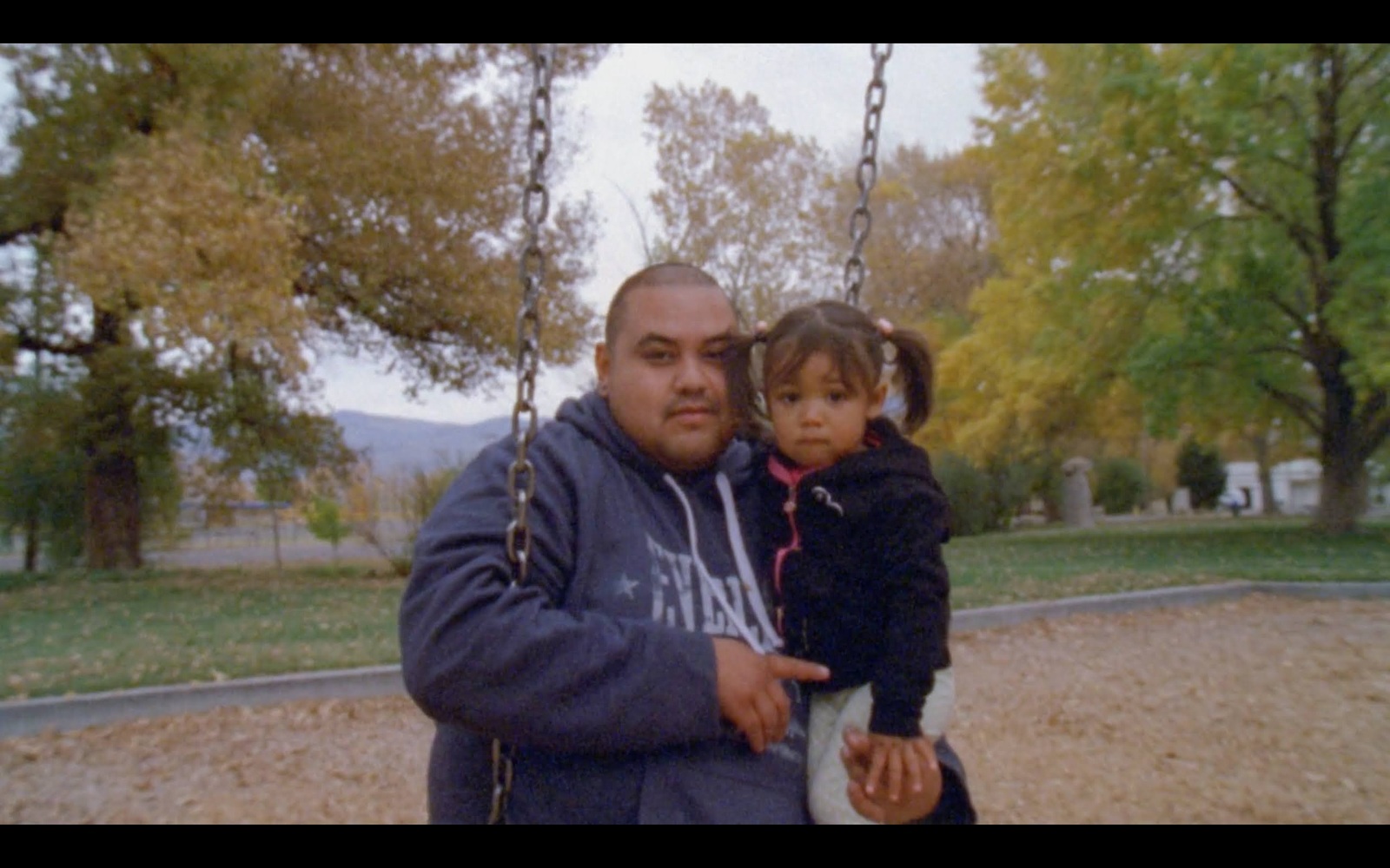 a man holding a little girl on a swing