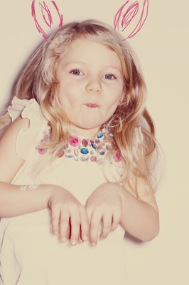 a little girl wearing bunny ears and a white dress