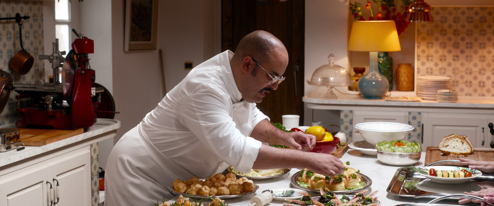 a man in a white chef's coat preparing food on a table