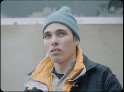 a young man wearing a blue and yellow jacket and a beanie