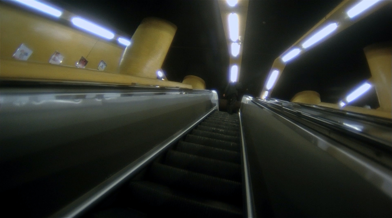 an escalator in a subway station with yellow railings