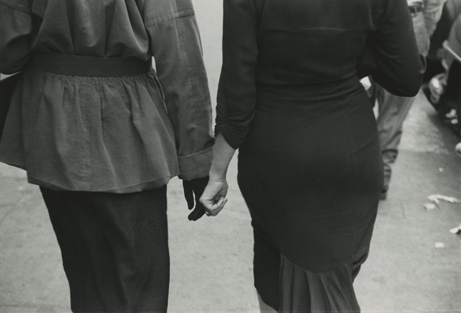 a black and white photo of two people holding hands