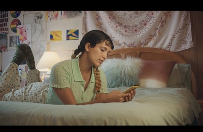 a woman laying on a bed looking at a cell phone