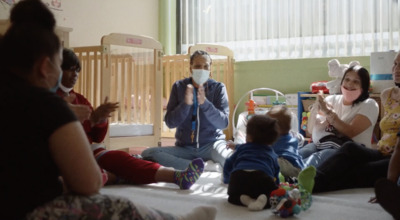 a group of people sitting around a baby in a crib