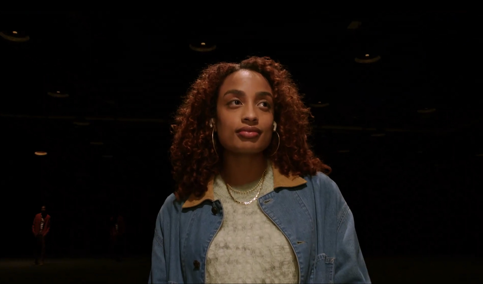 a woman with curly hair standing in the dark