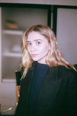 a woman in a black jacket is standing in a room