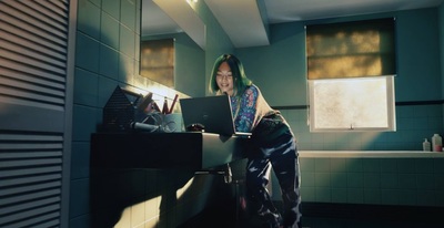 a woman standing in a bathroom using a laptop computer