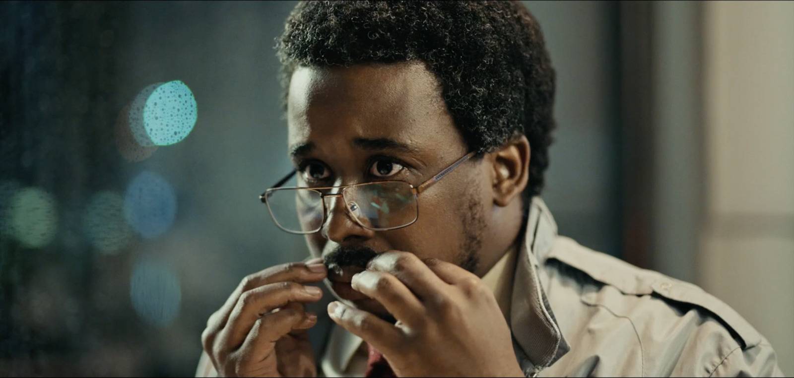 a man with glasses eating a piece of food