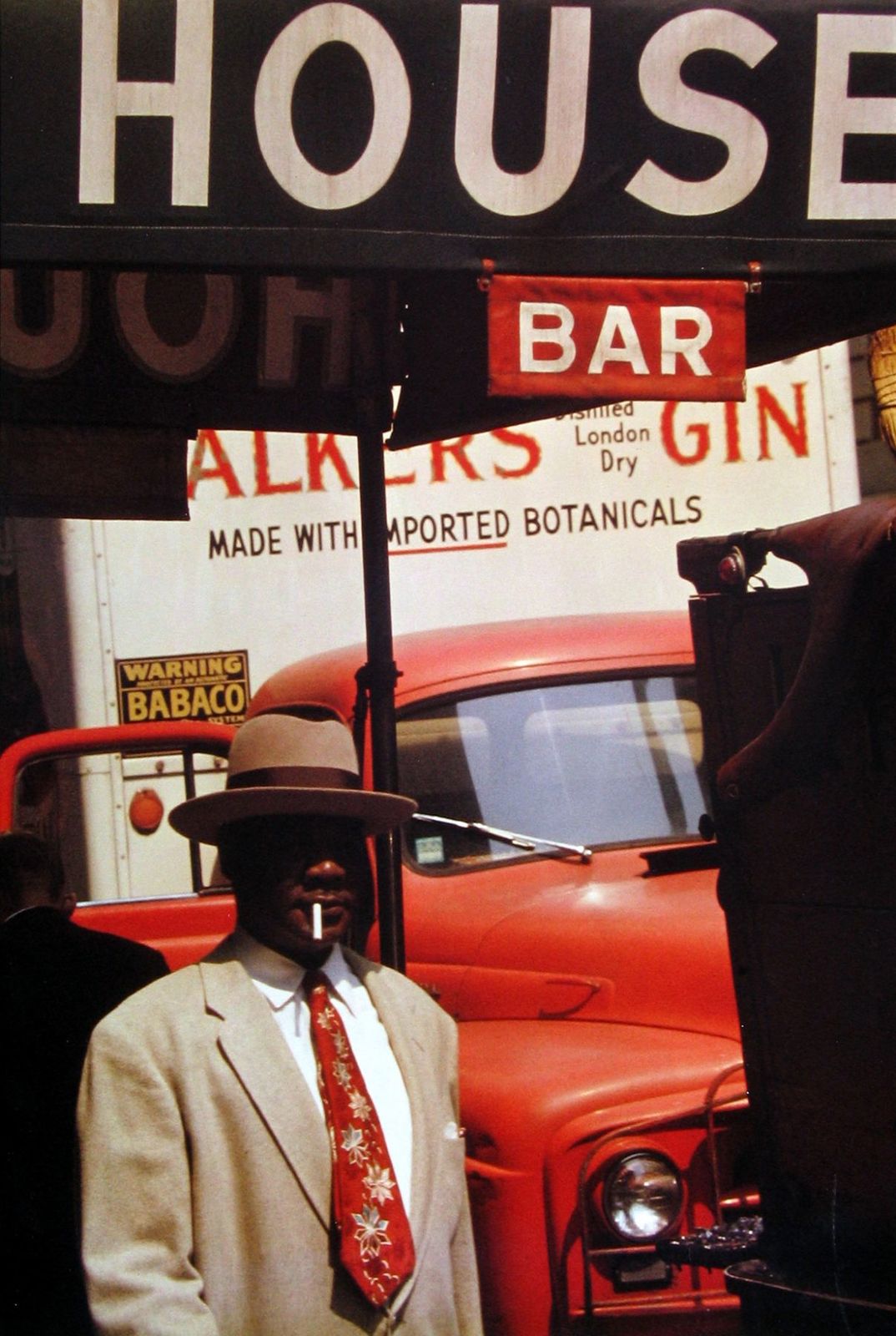 a man in a suit and tie standing under a sign