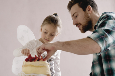 a man and a little girl are cutting a cake