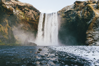 a large waterfall with a man standing in front of it