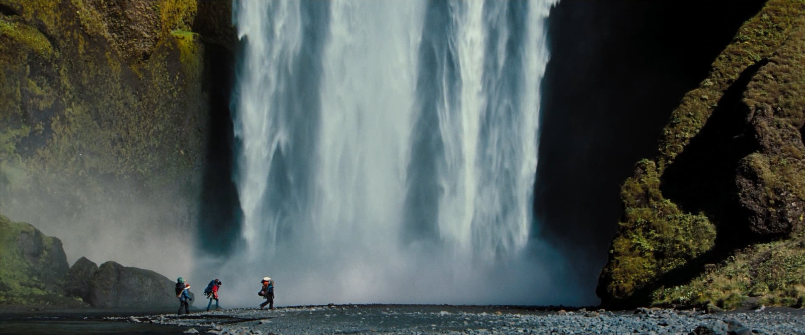 a group of people standing in front of a waterfall