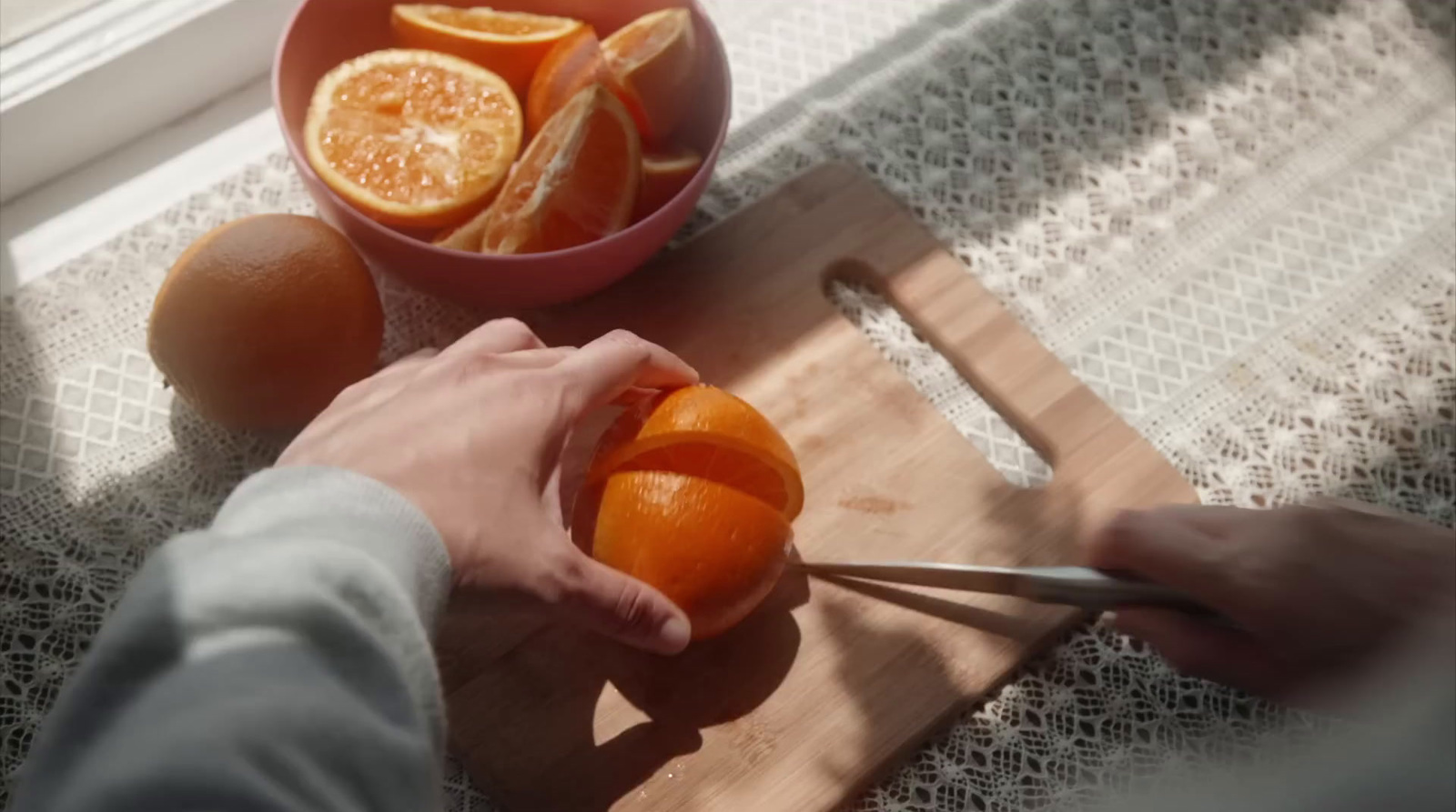 a person cutting an orange on a cutting board