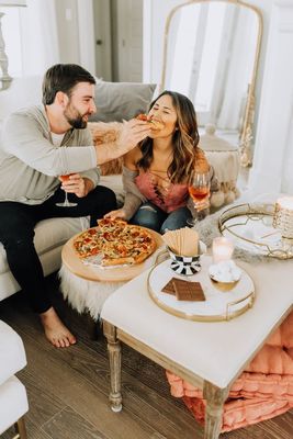 a man feeding a woman a piece of pizza