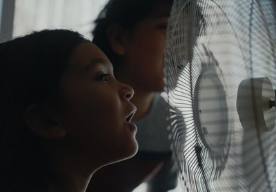 a girl and a boy looking at a fan