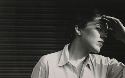 a black and white photo of a woman covering her eyes