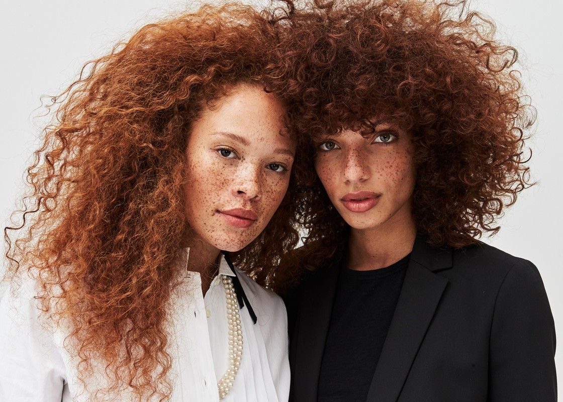 two women with curly hair posing for a picture