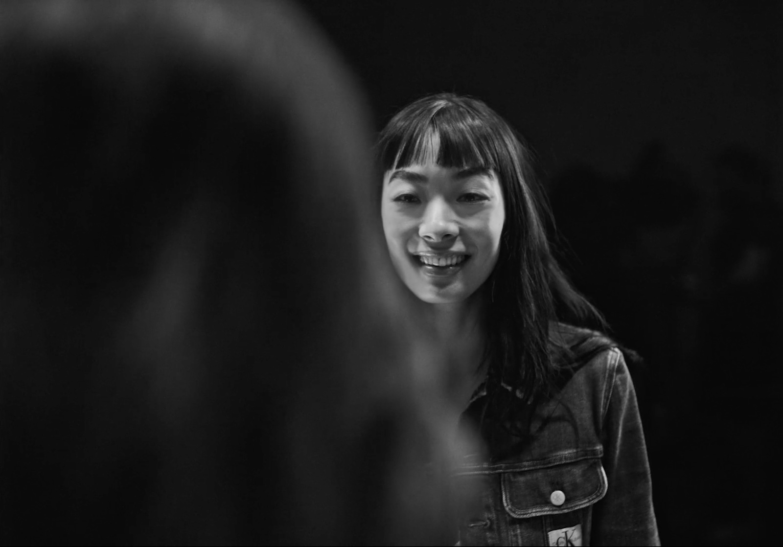 a young girl smiles as she stands in front of a mirror