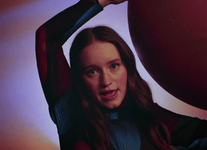 a woman holding a large red object over her head