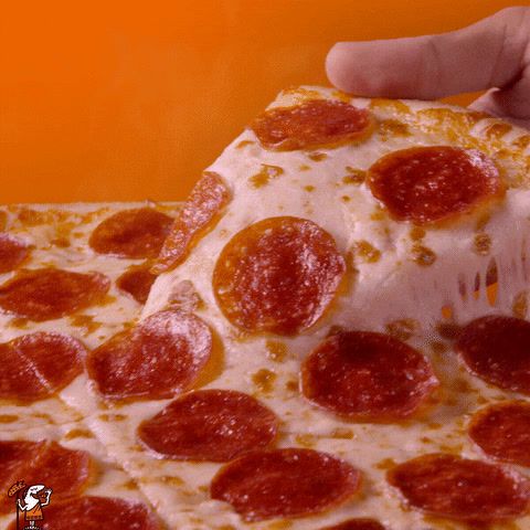 a pepperoni pizza is being held up by a hand