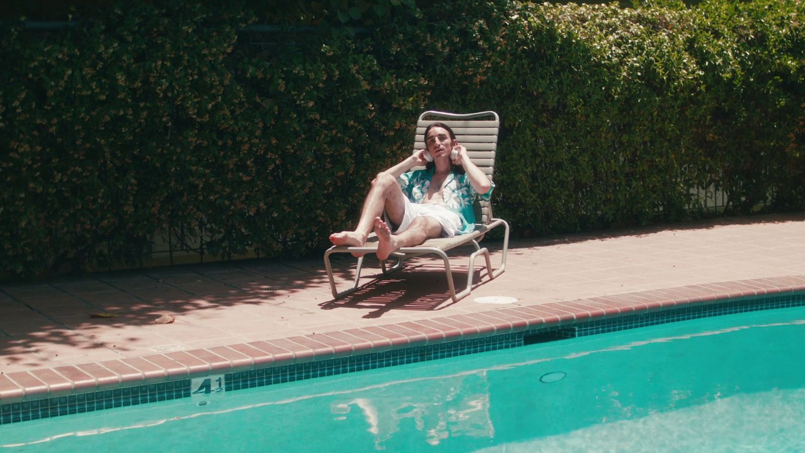 a man sitting in a lawn chair next to a swimming pool