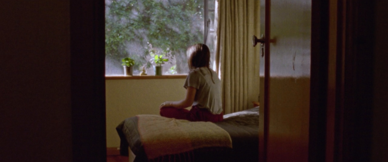 a woman sitting on a bed looking out a window