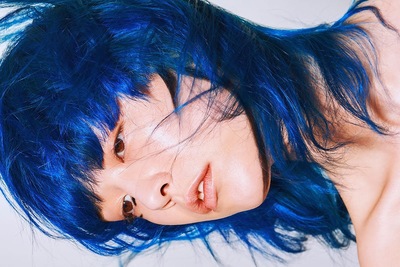 a woman with blue hair laying on top of a bed