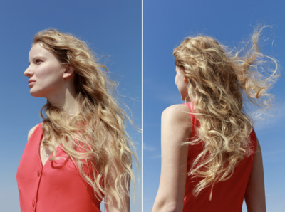 a woman with long blonde hair standing in front of a blue sky